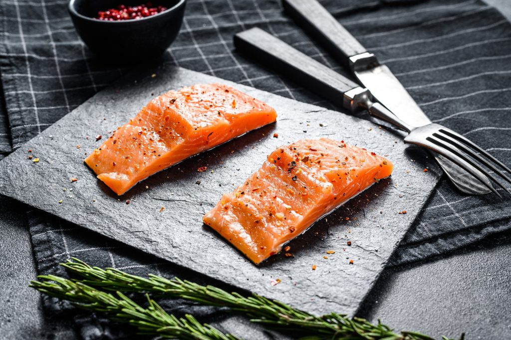 Fillet salmon steak on a stone Board. Black background. Top view